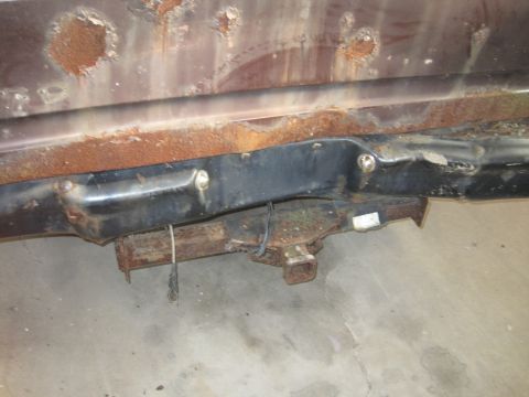 1979 Ford Bronco - Close-up of a heavily rusted vehicle frame and trailer hitch assembly.