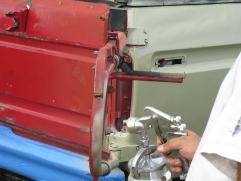 1978 Ford Bronco - Spray gun applying paint to a vehicle's door hinge assembly during restoration.