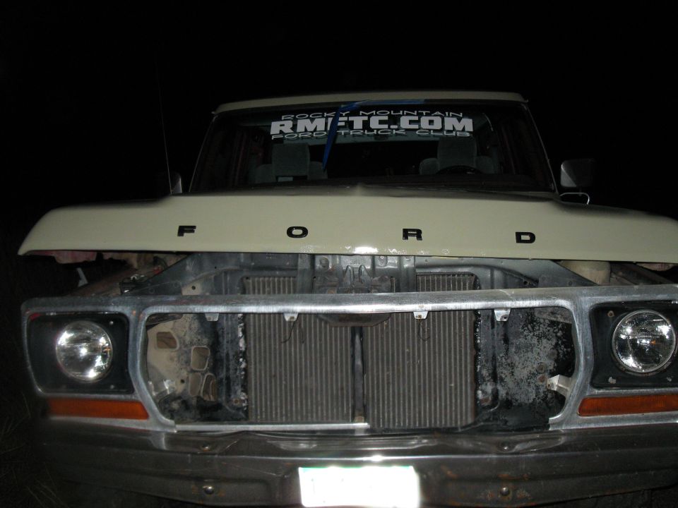 Front of a Ford truck with hood open, showing the grille and radiator. A sticker on the windshield reads 'ROCKY MOUNTAIN RMFTC.COM FORD TRUCK CLUB'