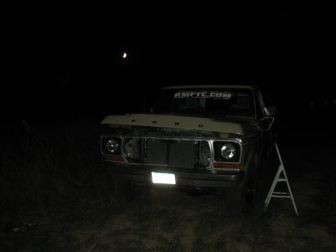 1978 Ford Bronco - A Ford truck is seen at night with its hood open and grille removed.
