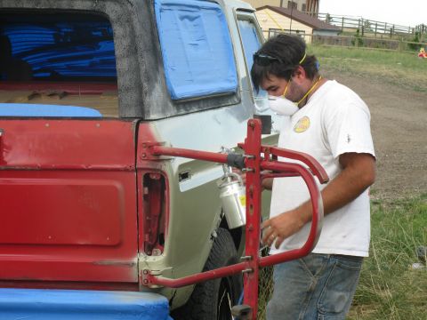 1978 Ford Bronco - A man sprays paint onto the rear quarter panel of a 1978 Ford Bronco during a restoration project.