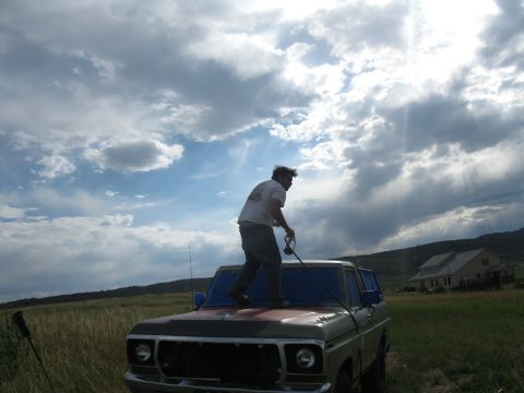 1978 Ford Bronco - A man stands on the hood of a classic truck in a grassy field under a dramatic sky.