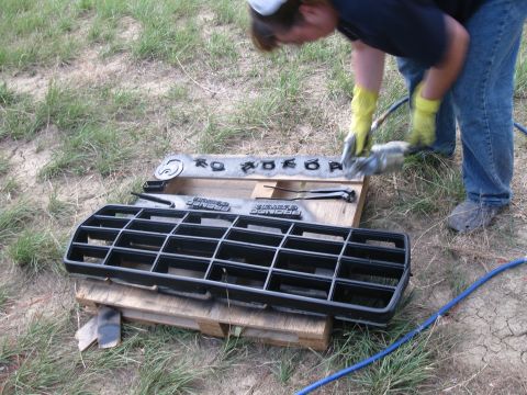 1978 Ford Bronco - A person is painting the grille and emblem of a 1978 Ford Bronco outdoors.