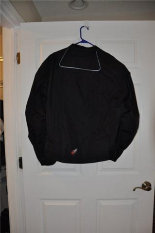 2008 Honda CBR-RR - Black motorcycle jacket with white trim and a small red and white logo on the lower back, hanging on a white door.