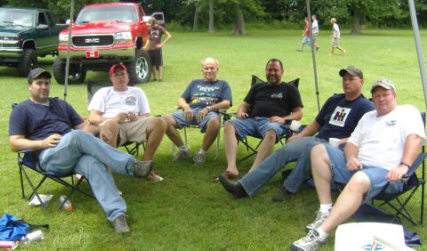 2007 Ford Mustang - Men gather outdoors with lifted trucks parked behind them.