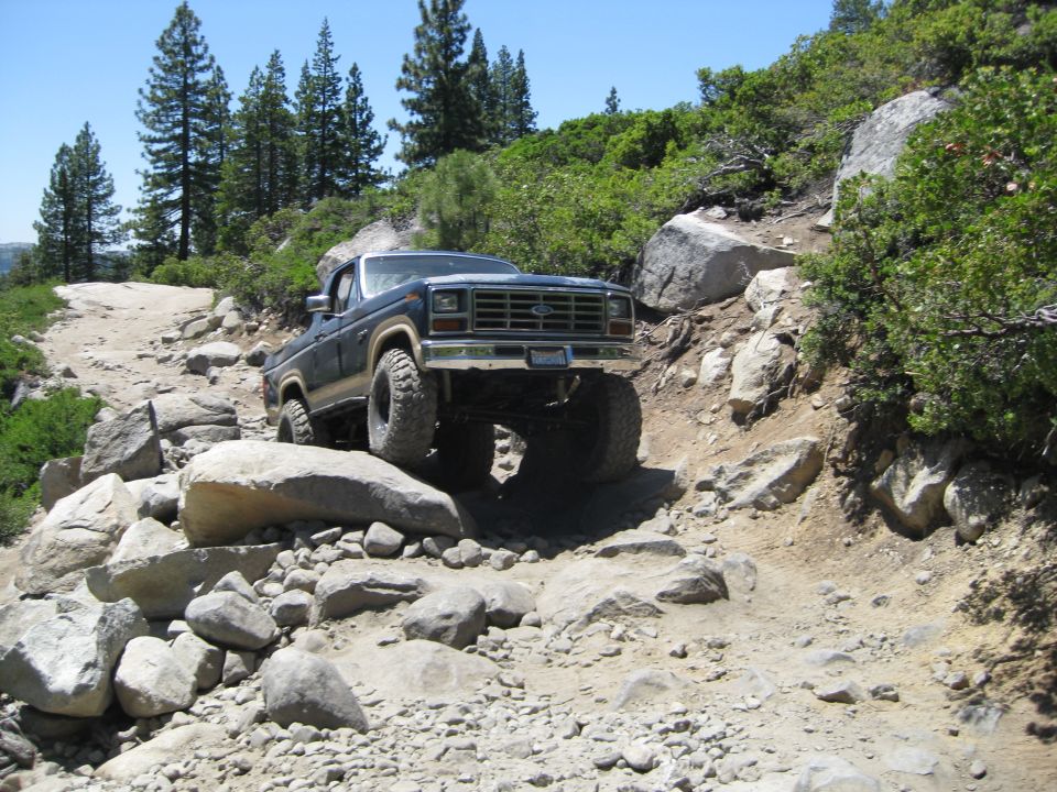 Dark blue 1980s 4x4 truck navigating a rocky trail
