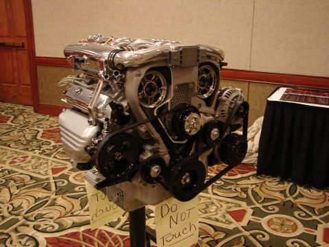 1992 Ford Taurus - A polished V8 engine is displayed on a stand, with cautionary signs placed nearby.