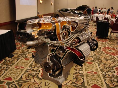 1992 Ford Taurus - A detailed cutaway engine display is shown at an event, with two cars visible in the background.