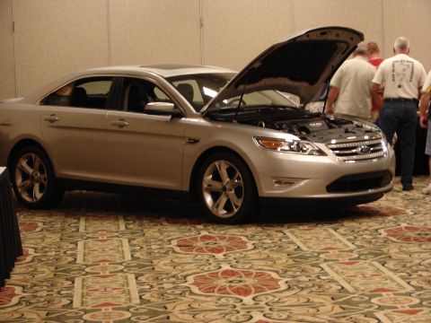 1992 Ford Taurus - Silver sedan with hood open at an indoor event. The car's grille and headlights are visible.