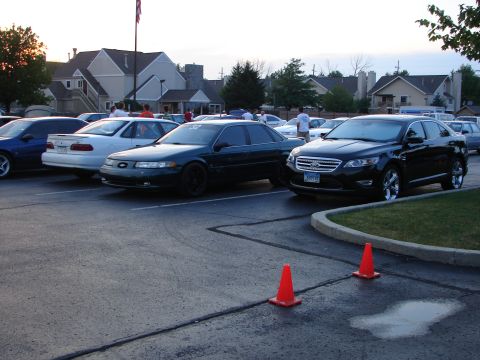 1992 Ford Taurus - A black sedan with chrome wheels is parked in a lot with other vehicles.