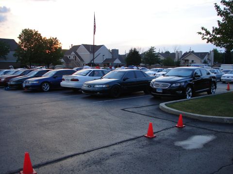 1992 Ford Taurus - A parking lot filled with various sedans, with buildings and trees visible behind them.