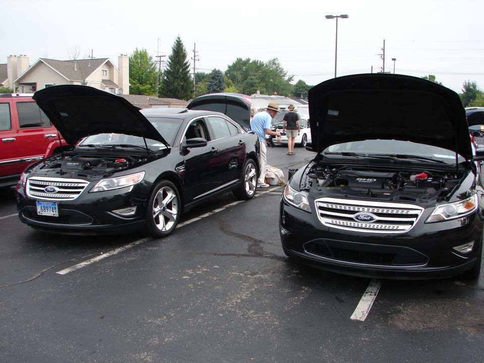 Two black Ford Taurus sedans, front view, hoods open