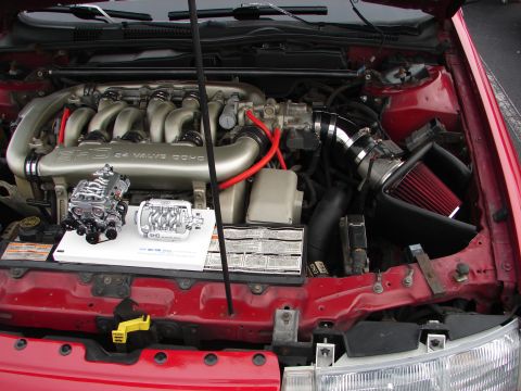 1992 Ford Taurus - Engine bay of a 1992 Ford Taurus SHO, its 3.0L V6 engine and display models of superchargers.