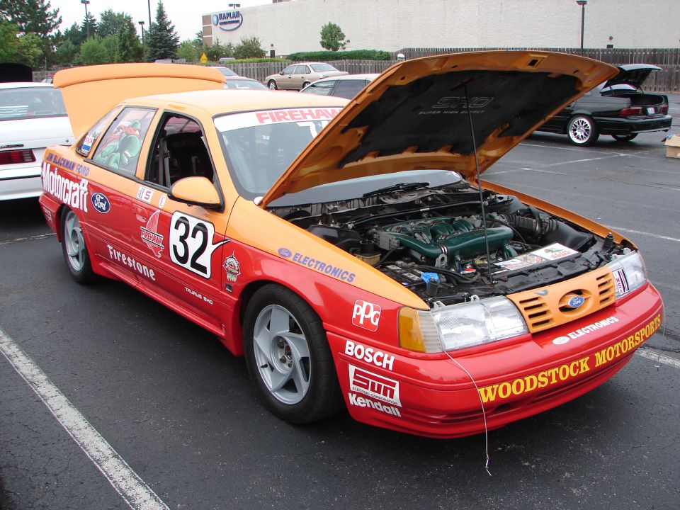 Orange and red 1992 Ford Taurus race car with hood open, number 32, and various sponsor decals