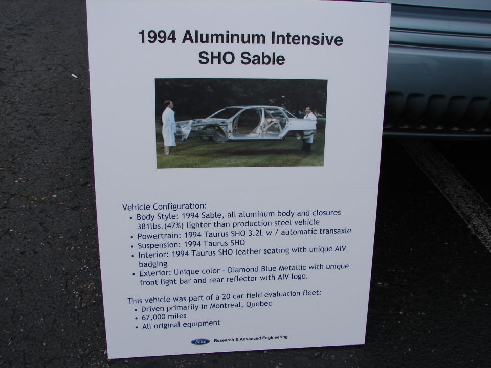 Sign about a 1994 Ford Taurus SHO Sable prototype, showing its aluminum construction and details. The car itself is visible in a photo on the sign