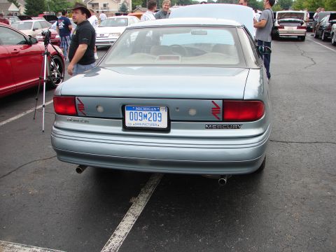 1992 Ford Taurus - A light blue Mercury Sable sedan is parked at an outdoor event with other vehicles and people around.