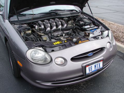 1992 Ford Taurus - Front view of a 1996 Ford Taurus with the hood open, showing the engine and V8 MTX license plate.