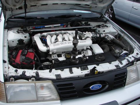1992 Ford Taurus - The engine bay of a white 1992 Ford Taurus, identified by its SHO 24V DOHC engine and Ford grille, is shown with the hood open.