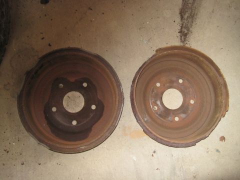 1979 Ford Bronco - Two heavily rusted brake drums are shown on a concrete surface, indicating wear and tear.