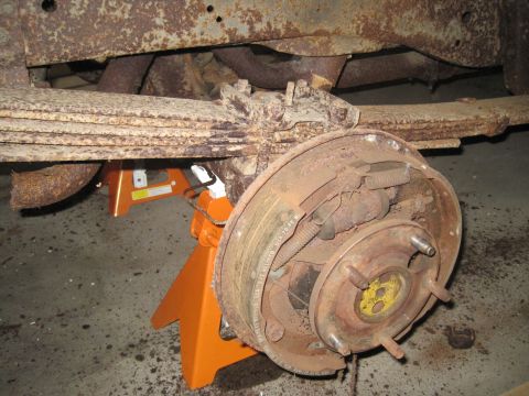 1979 Ford Bronco - Close-up of a rusty rear drum brake assembly supported by jack stands.