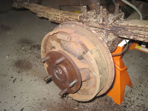 1979 Ford Bronco - Close-up of a heavily rusted rear drum brake assembly, likely from an older vehicle.