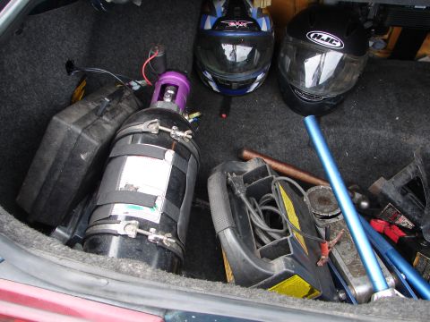 1992 Ford Taurus - The trunk of a car contains two helmets, a nitrous oxide tank, and various tools, including a jack.