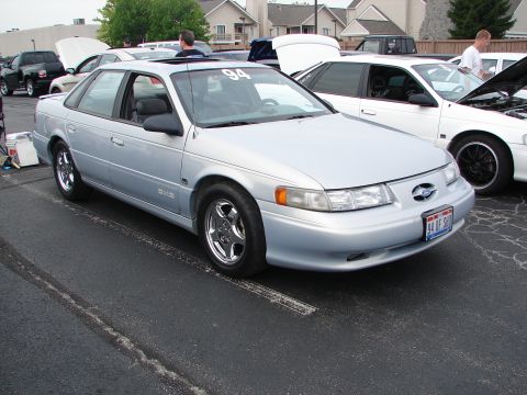1992 Ford Taurus - A silver 1992 Ford Taurus is parked at an outdoor event, with other vehicles visible in the background.