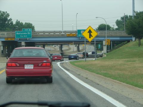 1992 Ford Taurus - A red 1992 Ford Taurus is seen from behind on a highway, approaching an exit.