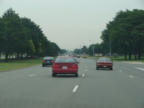 1992 Ford Taurus - A red 1992 Ford Taurus is seen from behind driving on a multi-lane road with other vehicles.