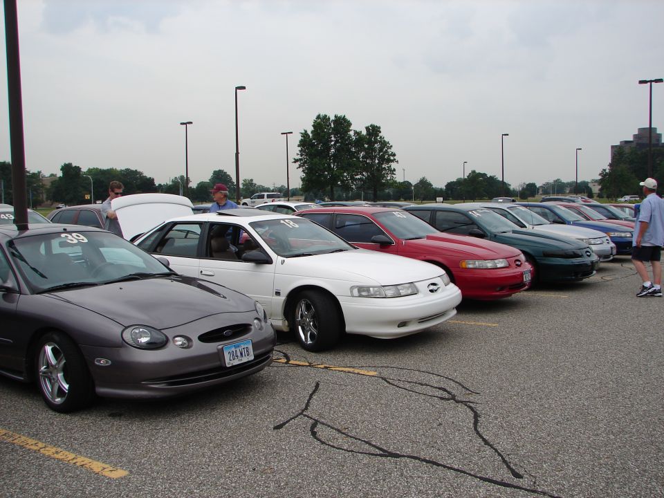 Several 1992 Ford Taurus cars parked in a lot, one with hood open. Number 39 on windshield of foreground car