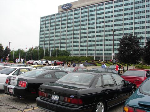 1992 Ford Taurus - A black Ford Taurus is parked in a lot with other vehicles in front of the Ford Motor Company headquarters.