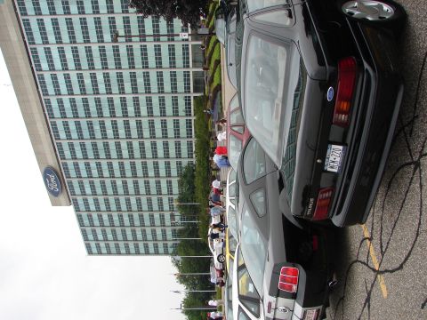 1992 Ford Taurus - A line of Ford vehicles are parked outside a modern office building with a Ford logo.