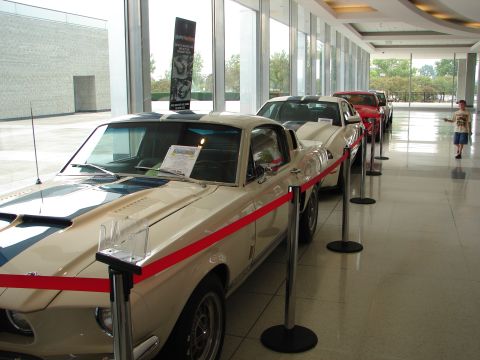 1992 Ford Taurus - A line of vintage Ford Mustangs are displayed indoors, with a young boy observing them.