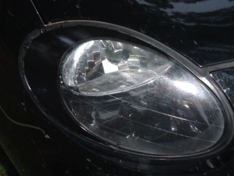 1999 Ford Taurus - Close-up of a black car's headlight, showing the clear lens and surrounding trim.
