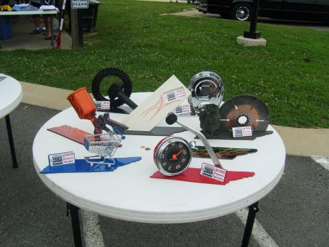 2007 Ford Mustang - Various automotive parts and novelty items are displayed on a table at an outdoor event.