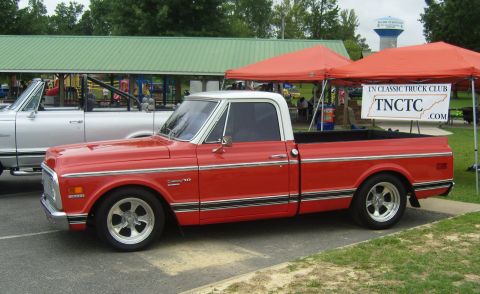 2007 Ford Mustang - A classic red pickup truck is displayed at an outdoor event, with a sign for the TN Classic Truck Club visible.