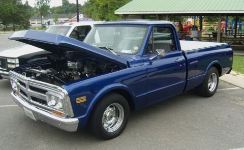 2007 Ford Mustang - A blue pickup truck, likely from the 1970s, is parked with its hood open, revealing the engine compartment.
