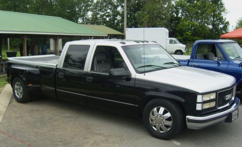 2007 Ford Mustang - A two-tone dually pickup truck is parked on a paved surface, with another truck visible to its right.