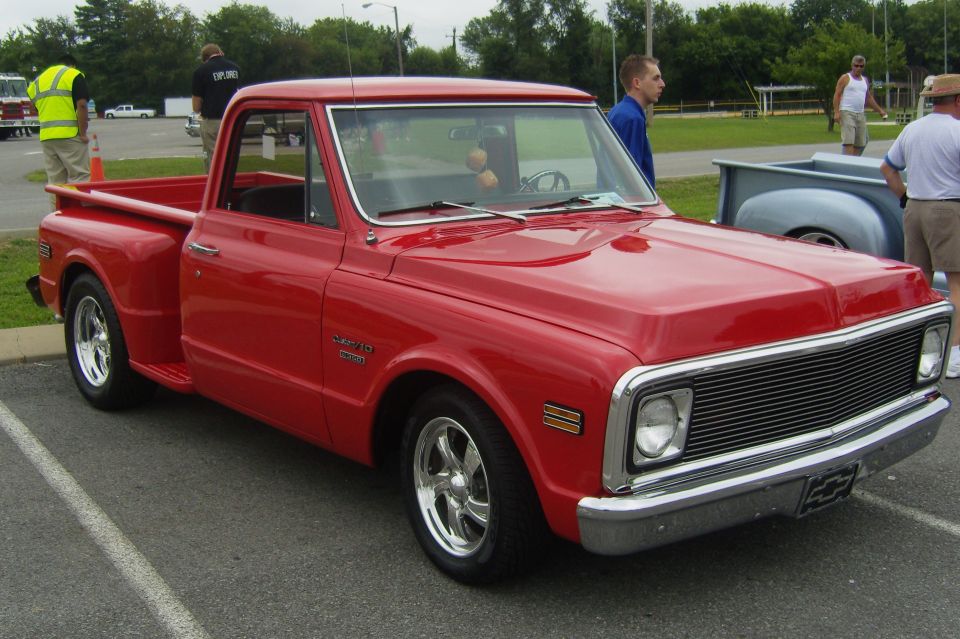 Red pickup truck with chrome grille and wheels, parked on asphalt