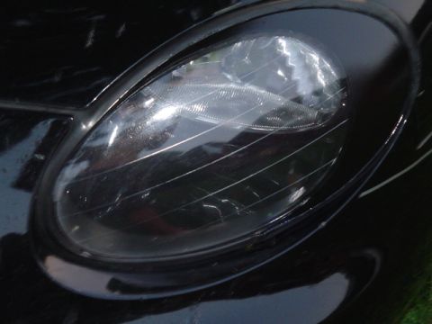 1999 Ford Taurus - Headlight detail on a black vehicle, showing scratches on the lens.