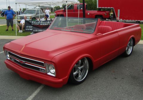 2007 Ford Mustang - Custom red convertible pickup truck at an outdoor event, with a Bullock's Body Works banner in the background.