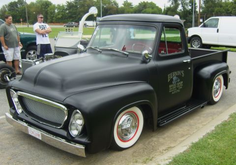 2007 Ford Mustang - A matte black pickup truck with custom wheels and red interior is parked on a curb.