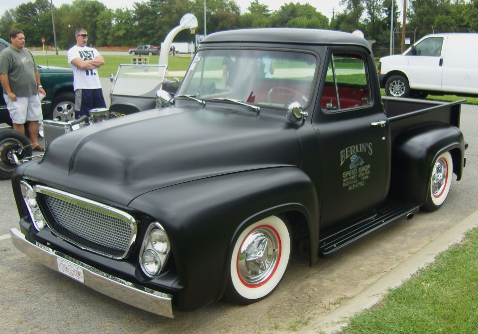 Matte black pickup truck with red interior and wide whitewall tires