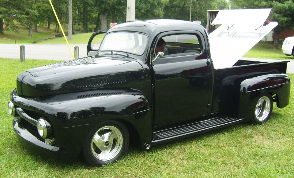 Black pickup truck with open driver's door and raised bed cover
