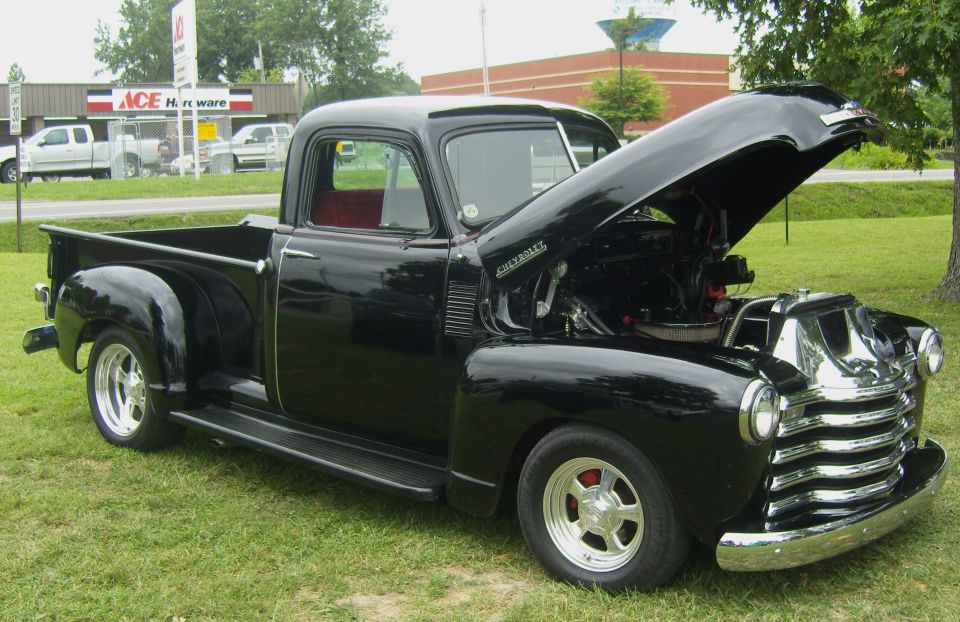Black 1950 Chevrolet pickup truck, hood open, showing engine
