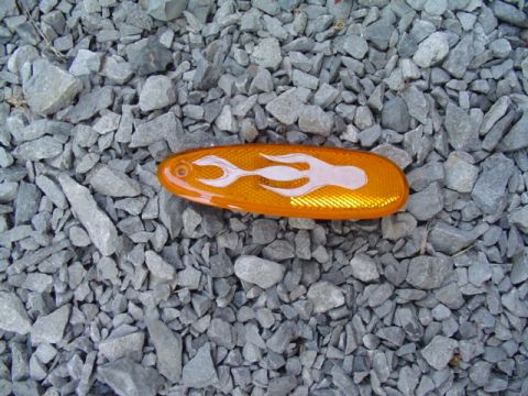 1999 Ford Taurus - An orange side marker with a white flame decal rests on a bed of gray gravel.