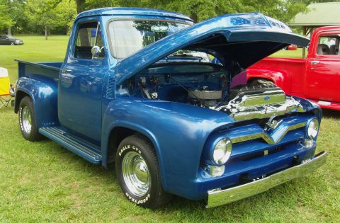 2007 Ford Mustang - Blue 1955 Ford F-series pickup truck with hood open, parked on grass next to a red truck.