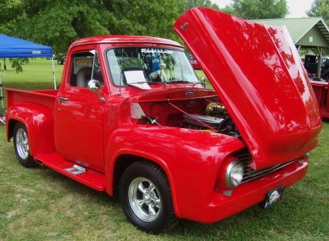 2007 Ford Mustang - A bright red 1956 Ford F-100 pickup truck is displayed with its hood open at an outdoor event.