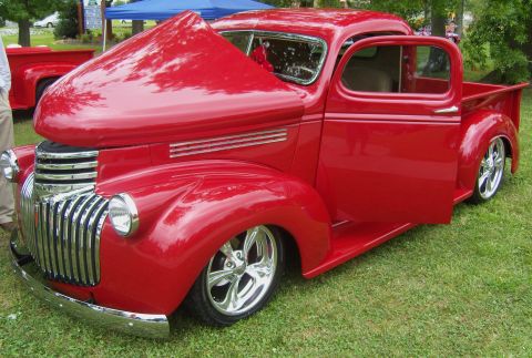 2007 Ford Mustang - A bright red classic pickup truck is displayed with its hood and driver's door open, revealing its interior and engine bay.