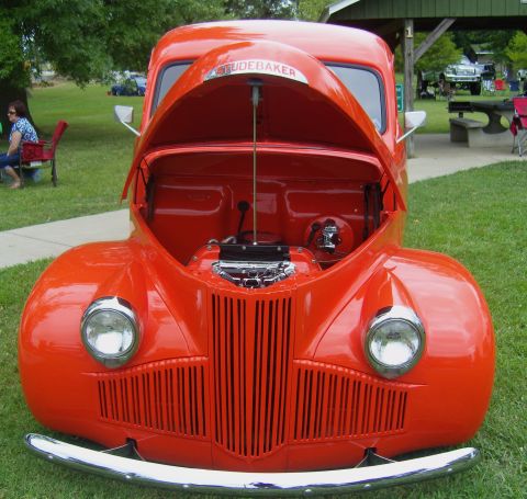 2007 Ford Mustang - An orange Studebaker truck is parked on grass with its hood open, revealing the engine compartment.